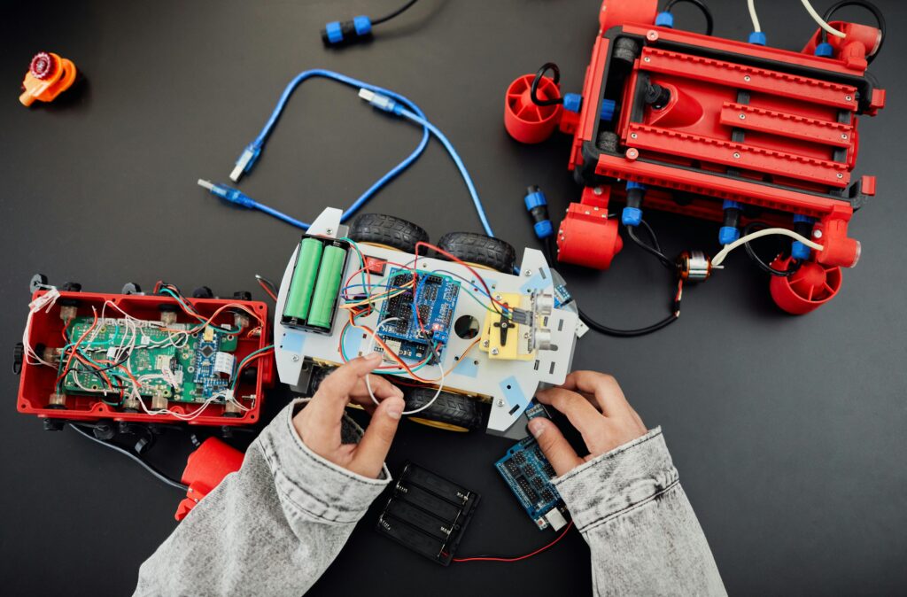 pexels photo 7868836 7868836 Young hands working on a robotics project with toy cars and circuits, focusing on innovation and education.