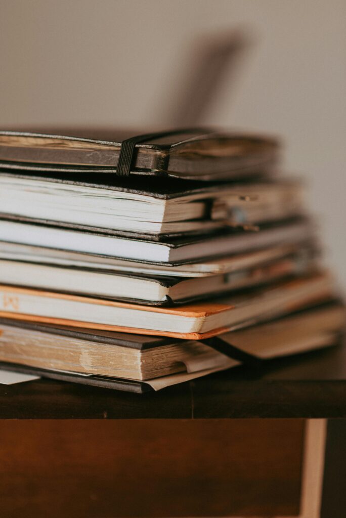 Close-up of stacked notebooks on a wooden table with warm lighting.