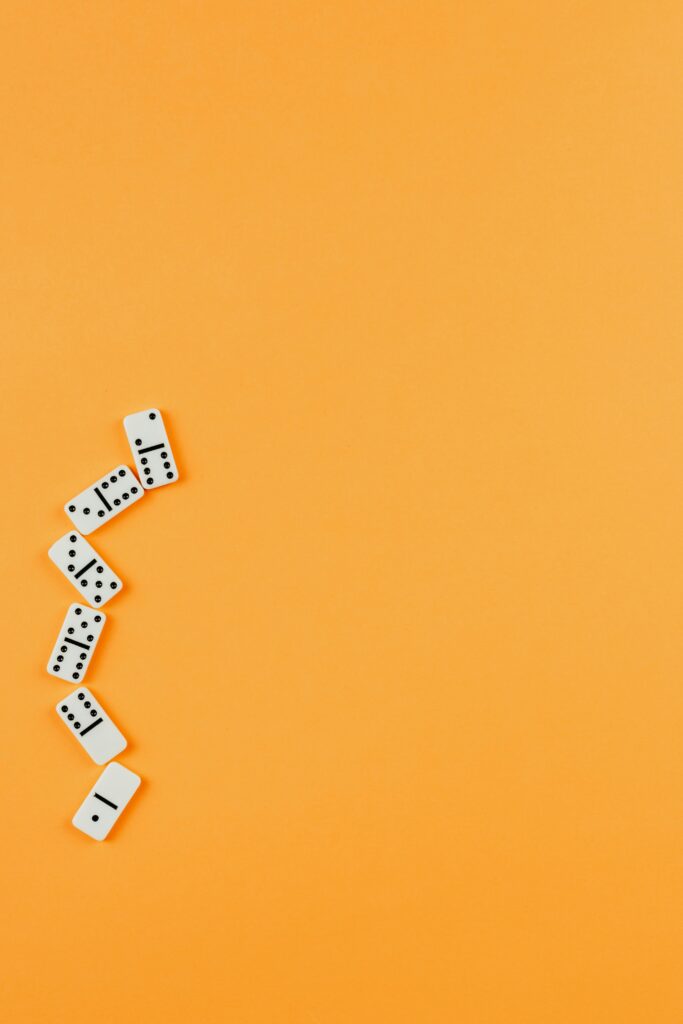A flat lay of domino pieces arranged artistically on a bright orange backdrop, showcasing clean and simple design.